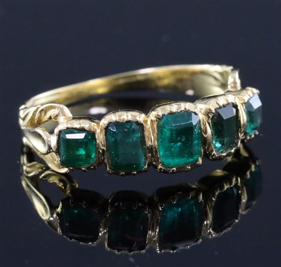 An early Victorian gold and foil backed? emerald five stone half hoop ring, size L.